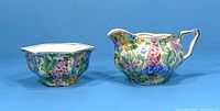 Ceramic cream pitcher and sugar bowl side by side showing floral chintz pattern and shape details