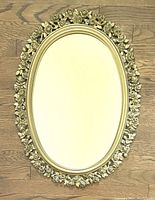 Full front view of the vintage oval mirror showing the gilt rose detailed frame on wooden floor.