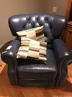 Front view of blue leather recliner with two striped pillows on seat