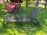 Side angle view of metal chaise lounge on grass showing lattice seat and adjustable backrest