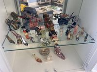 Top view of miniature shoes and handbags displayed on glass shelf, showing various styles and colors.