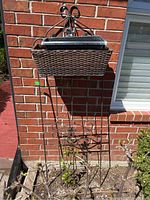 Front view of metal trellis with two planters attached, against a brick wall