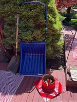 Photo of metal tree stand, Garant push shovel with blue blade, and standard shovel arranged outdoors on a deck.