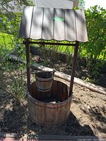Front view of the wood decorative wishing well showing round base, roof, and bucket inside.