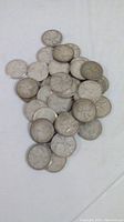 Pile of approximately 30 circulated silver Canadian quarters on white background
