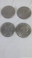 Four Eisenhower Bicentennial US one dollar coins laid in two rows of two. The top coins show the obverse (front) side featuring President Eisenhower's profile. The bottom coins show the reverse side with the Liberty Bell and moon design, the 1776-1976 dual date and 'United States of America' and 'One Dollar' inscriptions.