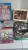 Group photo of all five cat-themed jigsaw puzzle boxes stacked and displayed on a table