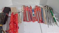 Large assortment of knitting needles in cloth cases and loose, showing overall collection and some case wear