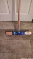 Photo of Marino 18 inch pushbroom including natural wood handle, metal connector and broom head with brown bristles and brand packaging.