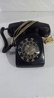 Front view of black Northern Telecom rotary phone showing rotary dial, handset, and attached cord.