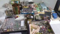 Wide view of assortment of tins, plastic organizers and sewing materials spread out on table.