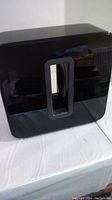 Front view of glossy black subwoofer on white surface
