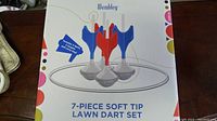 Box front showing product image of 4 darts and ring; text states '7-piece soft tip lawn dart set' with a note that includes 4 darts, 2 targets and carry bag.