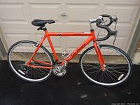 Side profile view showing the overall road bike with orange frame, drop handlebars with black tape, silver rims, and black seat with Tonino Lamborghini branding.