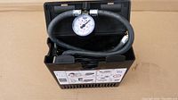 Front view of the Mercedes Benz mini air compressor showing the gauge, hose, and body with instructional label.