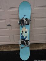 Full view of the 147 cm Kemper snowboard, blue with graphic design, bindings attached.
