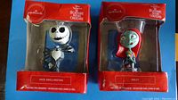 Two boxed Christmas tree ornaments of Jack Skellington and Sally in original Hallmark packaging, red themed boxes with branding and character names.