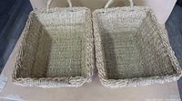 Two rectangular wicker baskets with woven handles on short sides, viewed from above showing interior and base weave detail.