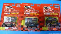 Three Racing Champions NASCAR die-cast stock car models in original packaging side by side, showing front view with driver photos and branding.