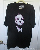 Black XL t-shirt with Bill Murray graphic on front hanging on hanger against a door.