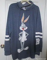Full front view of blue Bugs Bunny sweatshirt hoodie hanging on a hanger, showing graphic print and sleeve details.