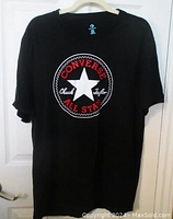 Front of black Converse t-shirt showing large circular Chuck Taylor patch with red, white, and black colors