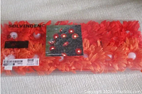 Photo showing the packaged IKEA Solvinden flower LED string lights with bright orange flowers and visible white LED bulbs inside clear plastic wrapping.