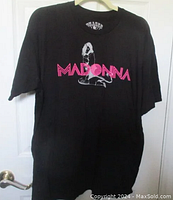 Full front view of the black Madonna T-shirt on a hanger showing the graphic and text design.