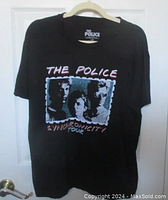Full front view of black T-shirt on hanger showing band graphic and text.