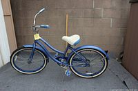 Side profile of the Huffy 24" Cranbrook girls' cruiser bike in periwinkle blue showing frame, saddle, tires, pedals, and kickstand.
