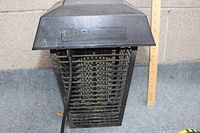 Front view of the electrical bug zapper showing its rectangular shape with protective grid and power cord. Ruler next to it indicates height approximately 13 inches.