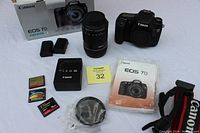 Full kit arranged on table showing camera body, lens, batteries, charger, memory cards, filter, manual, strap and box