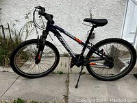 Left side view of the 24 inch Schwinn boys bike showing blue frame, front suspension, tires, kickstand, and pedals with reflectors.