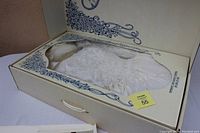 Wedding gown inside preservation box with clear window, showing lace and satin details.
