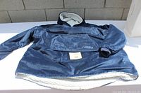 Blue wearable blanket laying flat showing overall design and sherpa lining at bottom and inside collar.