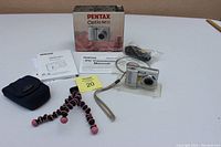 Photo shows the camera, soft case, flexible Joby tripod, instruction manuals, AV cable, and box on a white surface.