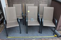 Six chairs arranged upright in two rows showing front view, charcoal frames and taupe mesh seats, measuring tape at base