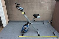 Front angled view of the stationary bike showing the seat, pedals, and digital monitor on the handlebar