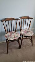 Pair of antique 1919 wooden bedstead spring and overlay chairs with matching floral seat pads, showing overall condition and style.