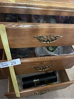 Two lower drawers partially open with a black cylindrical item, some bags and other miscellaneous items.