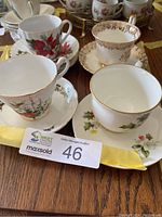 Four assorted china teacups on saucers with varying Christmas floral and gold rim designs.