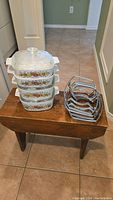 4 stacked Corning Ware casserole dishes featuring the Spice of Life pattern with 4 metal wire racks on the side.