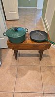 Dutch oven and skillet side by side on wooden bench