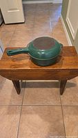 Green enameled pot with lid that also serves as a frying pan, shown upside down.