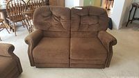Front view of brown corduroy reclining loveseat showing full loveseat and tufted back cushions.