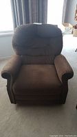 Front view of the brown corduroy rocker recliner chair showing plush seat and backrest, armrests, and lever on side.