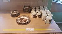 Photo of the entire china set showing stacks of bread plates, sandwich plates, saucers, teacups and coffee mugs with the brown Romantic England pattern.