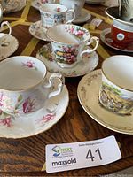 Image showing four vintage china teacups and their matching saucers on a wooden surface.