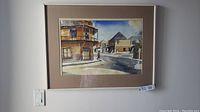 Front view of framed watercolor street scene by Anthony Law, silver metal frame with tan mat.
