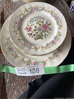 Stack of plates showing the floral Mandarin design with gold detailing and scalloped edges.